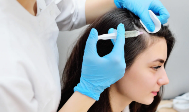 A woman in a medical setting getting therapy for hair growth from a skin care professional.